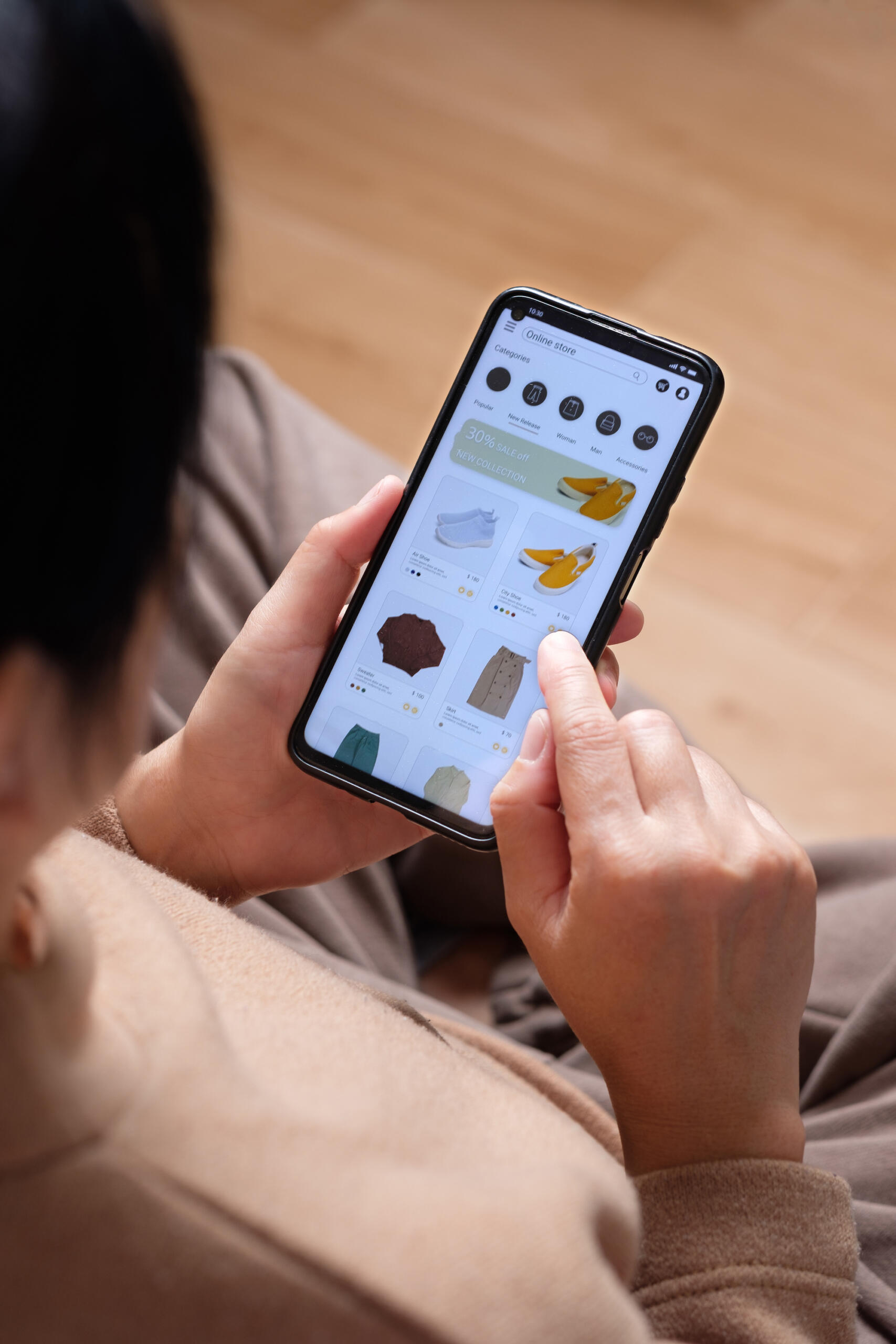 close up hand browsing shopping fashion mobile app on sofa at home