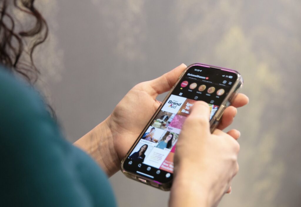 A hand holding an iPhone with Instagram open. The Instagram profile belongs to Asen Marketing, a marketing agency in Knoxville, Tennessee.