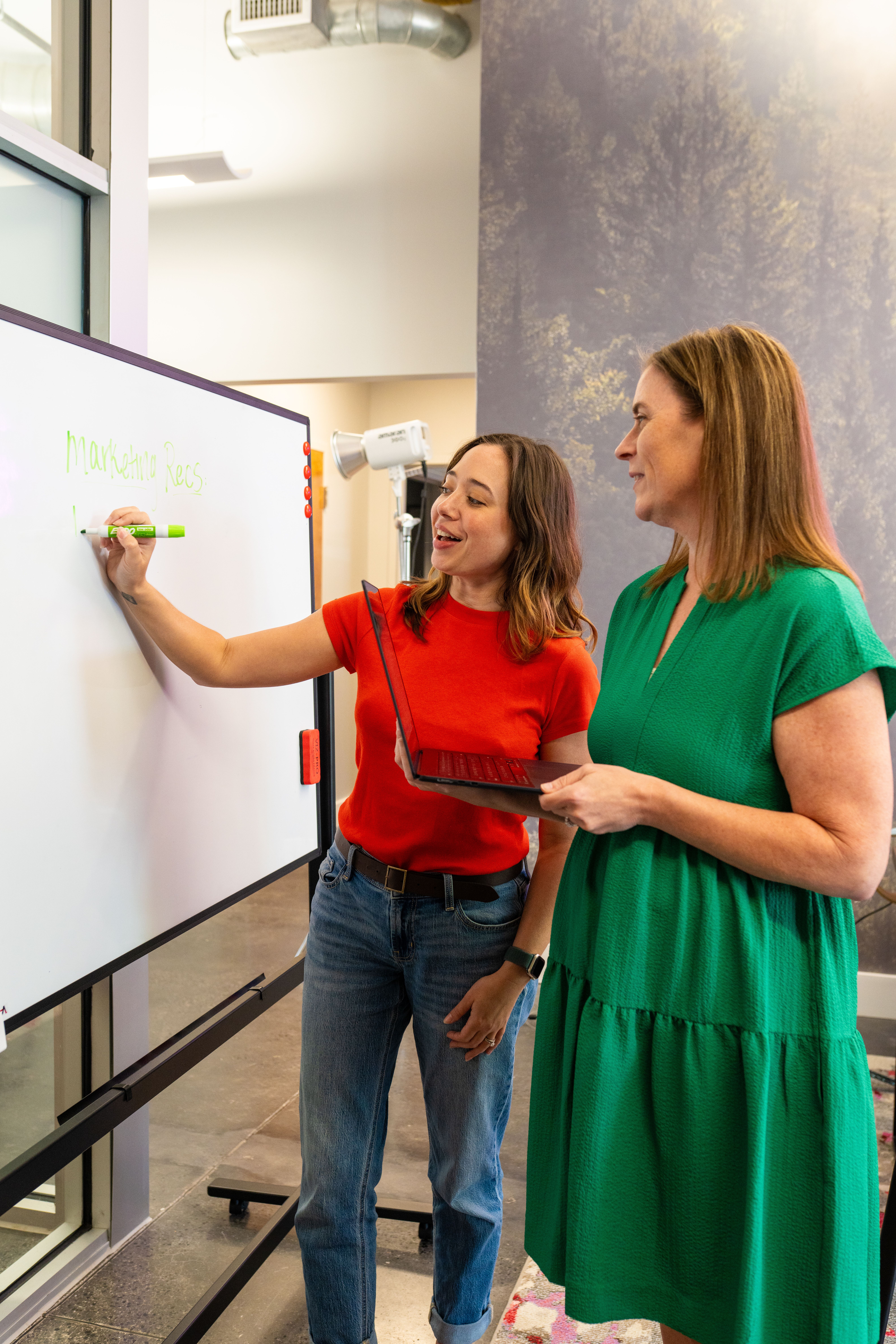 Two marketers standing at a white board working on building a strategic brand.
