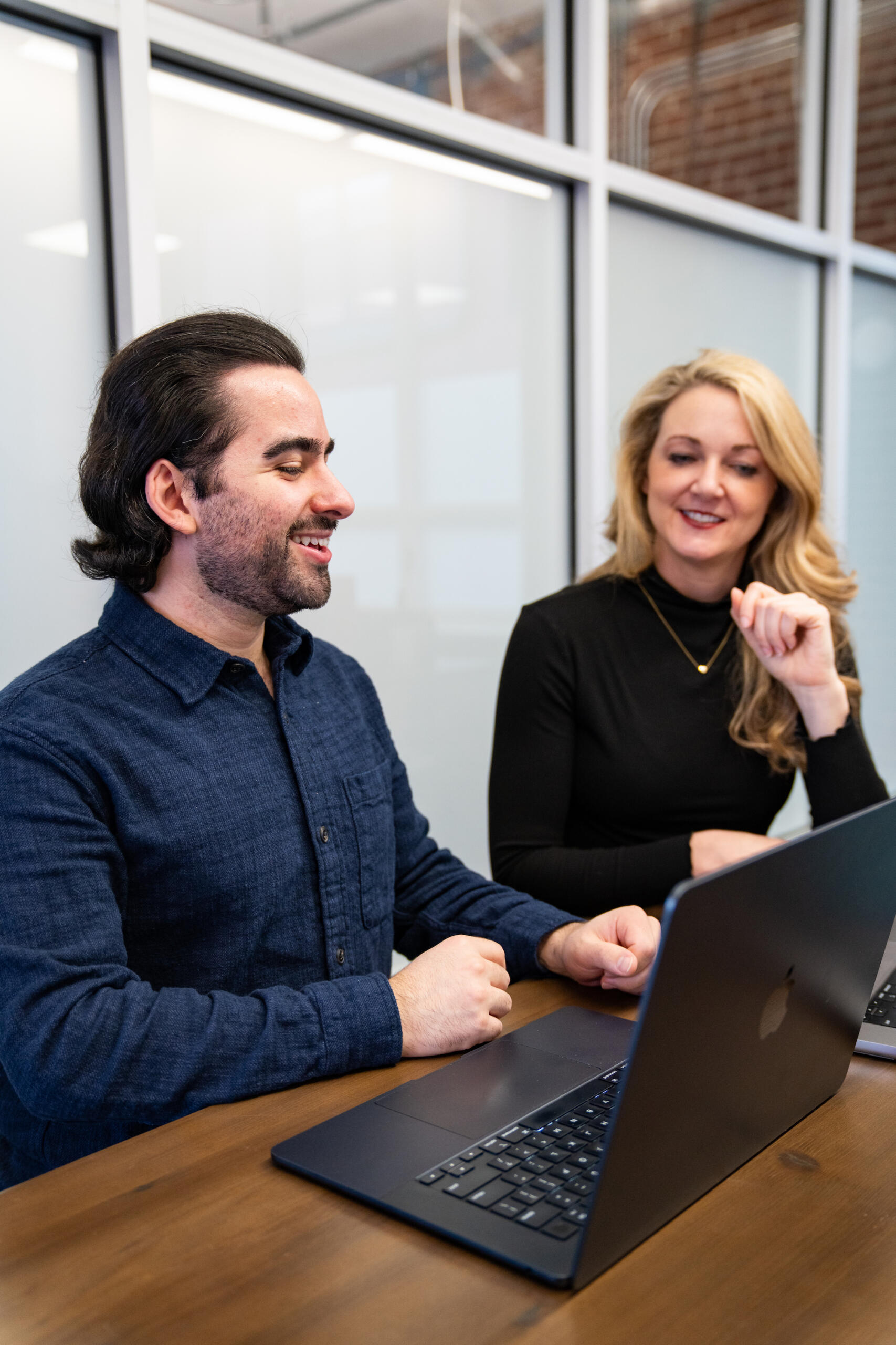 Two people talking near a laptop about the use of digital marketing tools like LLMs and AI
